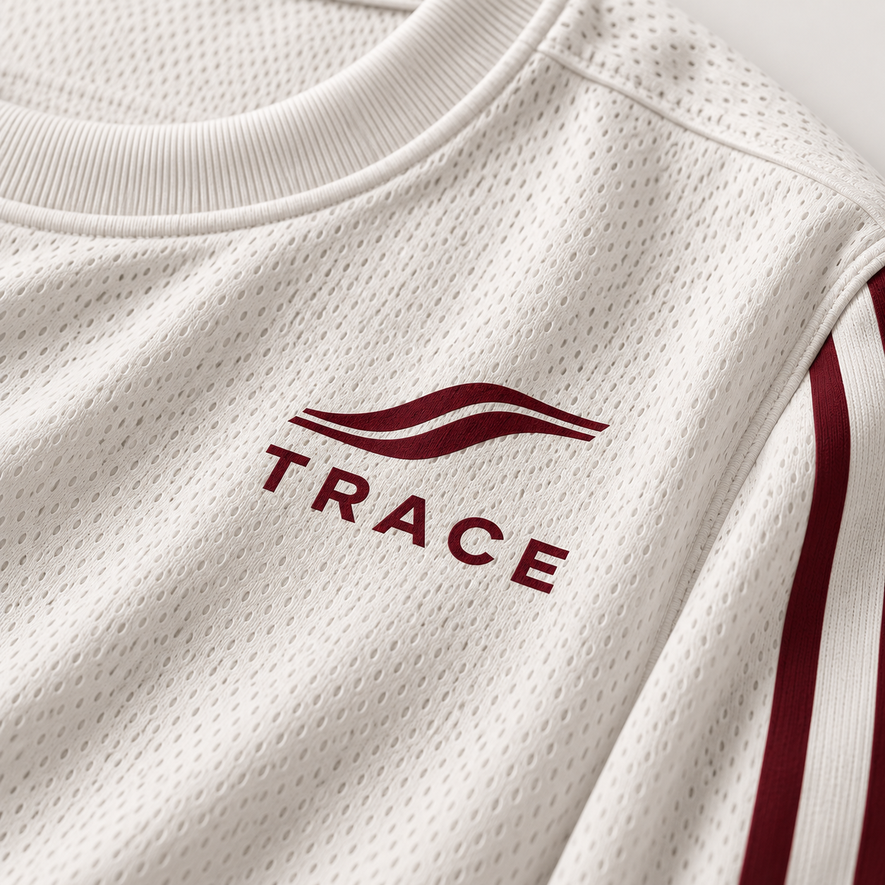 Close-up of the TRACE logo in burgundy on the white long sleeve
